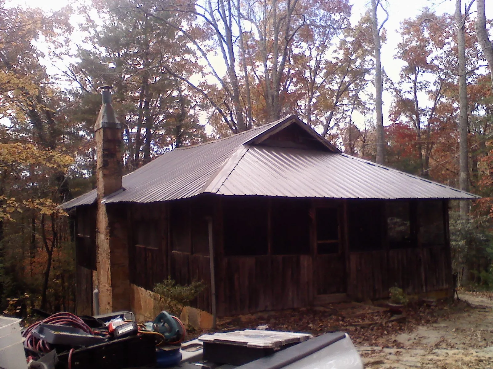 Brown metal hip roof on an old cabin with a stone chimney in Paradise