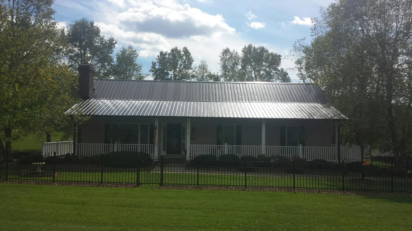 Gray metal roof on a brick ranch with a full width front porch — Gutter Guard Installation work by our crew in Paradise